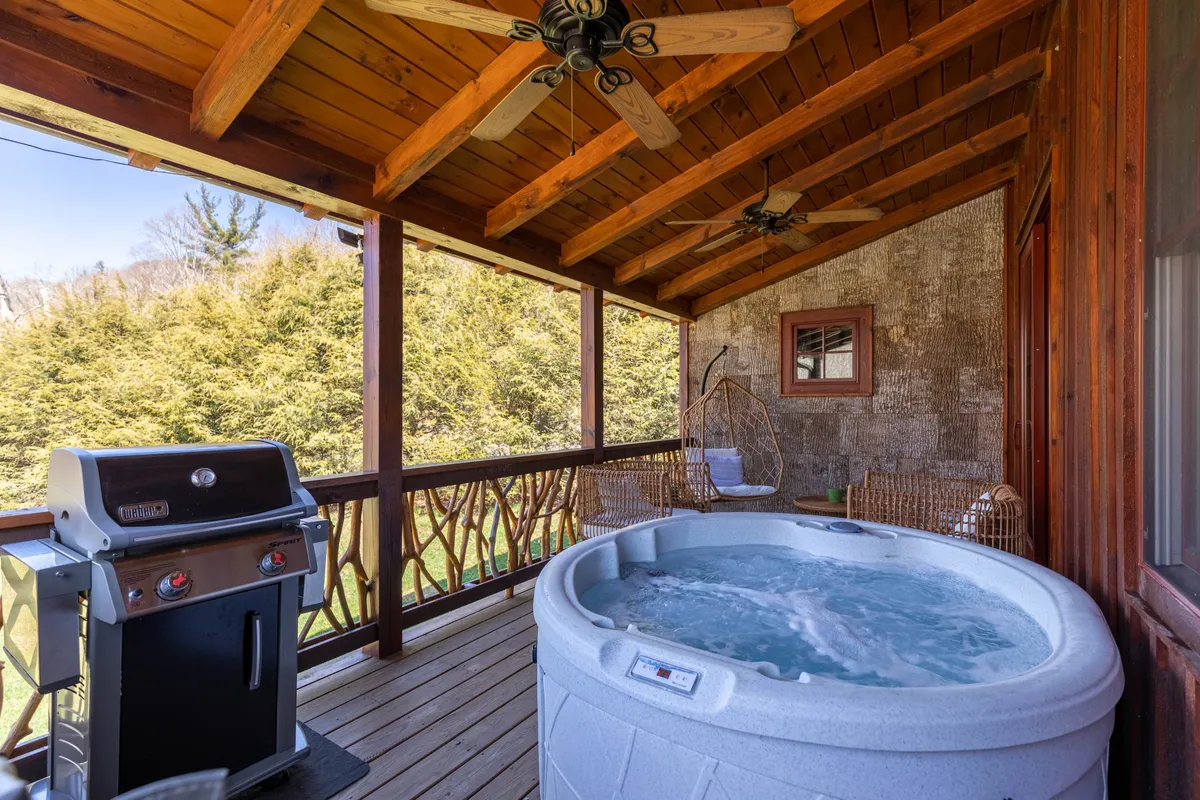 A close-up view of the deck's hot tub, surrounded by a grill and a hanging chair, immerses viewers in the inviting outdoor space. The tranquil setup is ideal for stargazing or peaceful mornings.